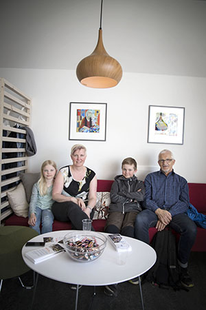 En äldre man, en kvinna och två barn sitter i en soffa.