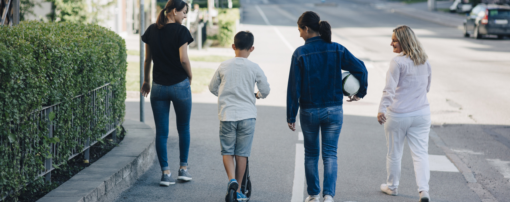 Tre vuxna och ett barn promenerar längs en stadsgata.