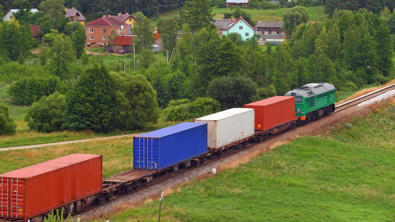 Tåg med lastvagnar kör genom öppet landskap i Sverige