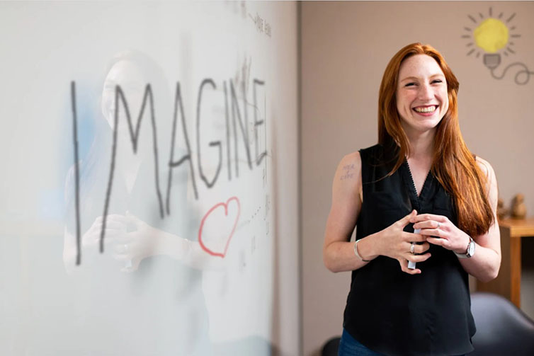 Kvinna står framför whiteboard där det står "Imagine".