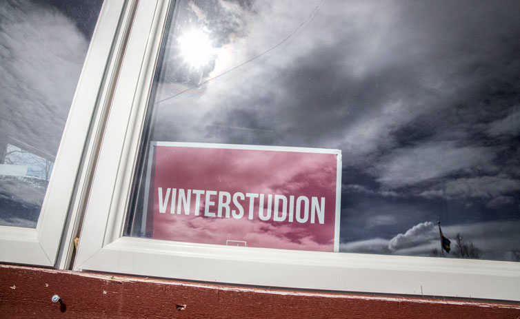 En skylt med texten "Vinterstudion" syns i ett fönster.