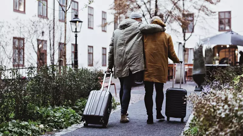 Två personer går med resväskor på en gata