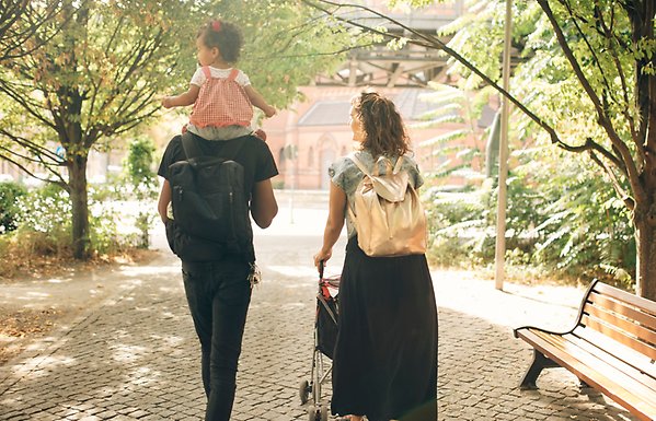 Man, kvinna och barn på promenad i en park